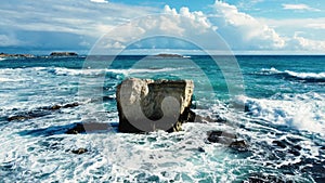 Ocean waves breaking on rocks at coast, aerial view seashore in stormy and sunny weather, Cyprus Nature