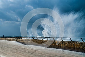 Ocean waves crashing against the edge of a sturdy pier, creating natural force and beauty
