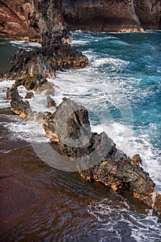 Ocean waves crashing on the rocky island coast. Splashing ocean waves and stones. Red Sand Beach, Maui in in Hawaiian.