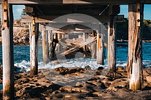Ocean waves crashing on the wooden poles of the Bare Island Bridge in La Perouse, Sydney