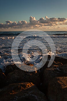 Ocean waves gently kiss sandy shore under twilight sky.