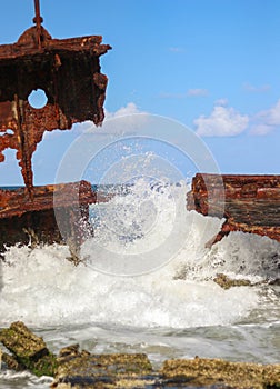 Ocean waves pound hard a rusted sunken ship stranded on the sand of Australia photo