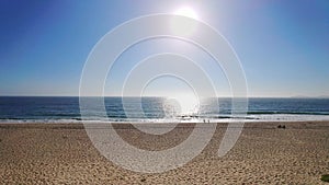 Ocean waves reflecting evening sun over a clear blue sky