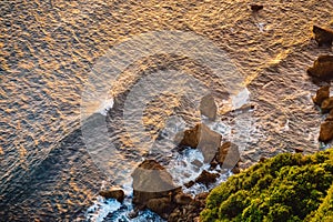 Ocean with waves, rocks and cliff at sunset or sunrice