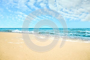 Ocean waves rolling on sandy beach under sky with clouds