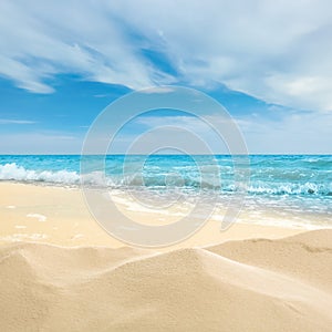 Ocean waves rolling on sandy beach under sky with clouds