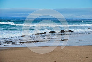 Ocean Waves rolling to the sandy beach, inhabitant land on the background. Ocean Grove, Victoria, Australia