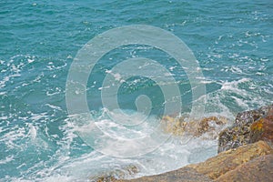 Splashes of waves crashing against the coastal stones.