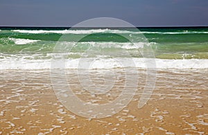 Ocean waves rushing to shore on a sandy beach