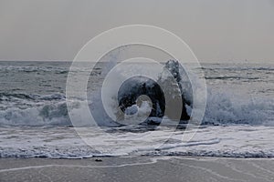 Ocean waves slam up against ice flows caught in the beach shallows