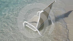 Ocean waves sweeping over beach chair in shallow ocean water