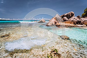 Ocean waves at tropical beach at Seychelles. Rocks on shore of La Digue Island