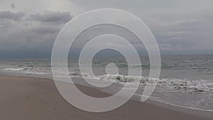 Ocean waves wash ashore a deserted beach under stormy skies, video.