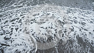 Ocean waves washing ashore creating texture from white foam, relaxation