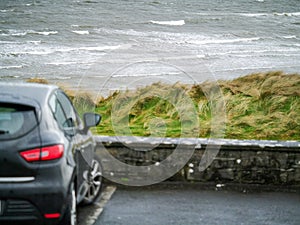 Ocean weaves in focus, Small black car out of focus in foreground. Rosses point, county Sligo, Ireland.
