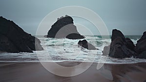 Ocean wild beach stormy weather at evening. Praia da Adraga sandy beach with picturesque landscape background, Sintra