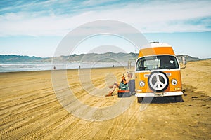 Vintage yellow van on the beach with cloudy sky on background, retro color effect. Oceano Dunes, California Central Coast