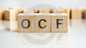 ocf - letters on wooden cubes. business as usual concept image. front view