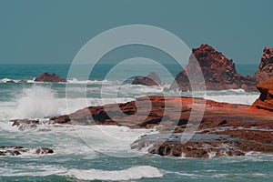 Ochre sandstone rock formations in Legzira Beach. Wild waters in Tiznit Province. Sea in Morocco, Africa. Atlantic Ocean waves.