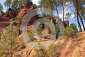 Ochre Trail in Roussillon, Hiking path in orange ocher cliffs surrounded by green forest in Provence, Southern France