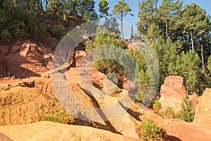 Ochre Trail in Roussillon, Sentier des Ocres, hiking path in a natural colorful area of red and yellow cliffs surrounded by green
