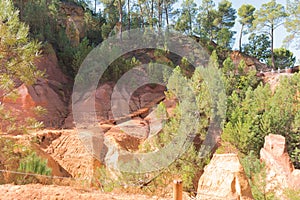 Ochre Trail in Roussillon, Sentier des Ocres, hiking path in a natural colorful area of red and yellow cliffs surrounded by green