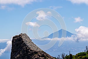 ock formation with scenic view on the cloud covered volcano mountain peak Pico del Teide on Tenerife seen from La Gomera