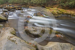 Oconaluftee River silky water cascading over and around borders