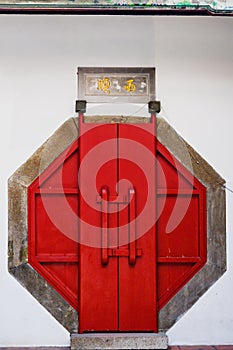 Octagonal red door, entrance to buddhist Taiwanese temple, Tainan, Taiwan