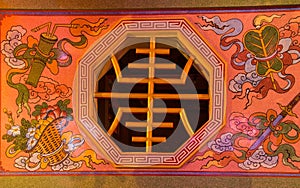 Octagonal window to the chinese temple with hieroglyph and decorated wall