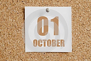 october 01. 01th day of the month, calendar date.White calendar sheet attached to brown cork board.Autumn month, day of