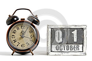 October 01 on wooden calendar with alarm clock white background.