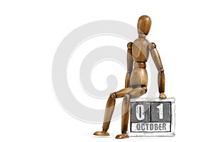 October 01, wooden calendar with mannequin sitting on it on white background. Calendar date.