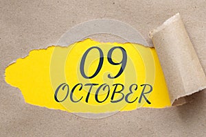 october 09. 09th day of the month, calendar date.Hole in paper with edges torn off. Yellow background is visible through