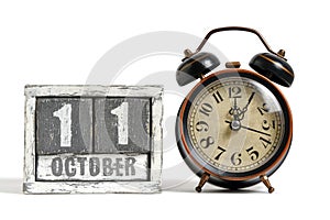 October 11 on wooden calendar with alarm clock white background.