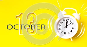 October 13rd. Day 13 of month, Calendar date. White alarm clock with calendar day on yellow background. Minimalistic concept of