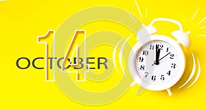 October 14th. Day 14 of month, Calendar date. White alarm clock with calendar day on yellow background. Minimalistic concept of