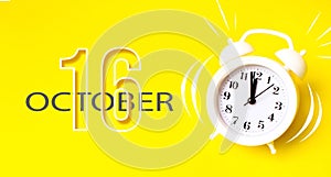 October 16th. Day 16 of month, Calendar date. White alarm clock with calendar day on yellow background. Minimalistic concept of