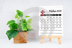 October 2024 calendar page and wooden plant pot