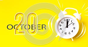 October 20th. Day 20 of month, Calendar date. White alarm clock with calendar day on yellow background. Minimalistic concept of