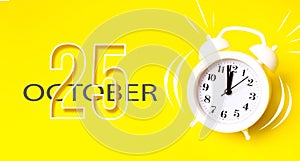 October 25th. Day 25 of month, Calendar date. White alarm clock with calendar day on yellow background. Minimalistic concept of