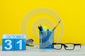 October 31st. Day 31 of october month, wooden color calendar on teacher or student table, yellow background . Autumn
