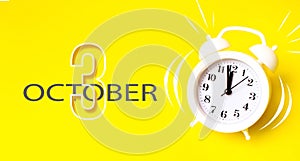 October 3rd. Day 3 of month, Calendar date. White alarm clock with calendar day on yellow background. Minimalistic concept of time