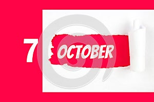 October 7th. Day 7 of month, Calendar date. Red Hole in the white paper with torn sides with calendar date. Autumn month, day of