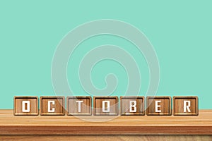 October alphabet blocks on wooden table with blue background photo