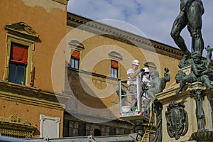 October 2021 Bologna, Italy: Workers cleaning the Neptune Fountain across the buildings on the square, piazza Maggiore