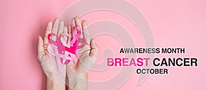 October Breast Cancer Awareness month, adult Woman hand holding Pink Ribbon on pink background for supporting people living and