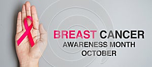 October Breast Cancer Awareness month, adult Woman  hand holding Pink Ribbon on grey background for supporting people living and