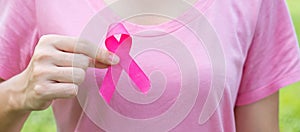 October Breast Cancer Awareness month, adult Woman in pink T- shirt with hand holding Pink Ribbon for supporting people living and