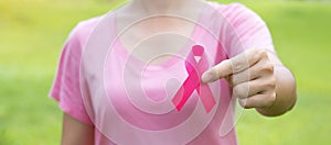 October Breast Cancer Awareness month, adult Woman in pink T- shirt with hand holding Pink Ribbon for supporting people living and
